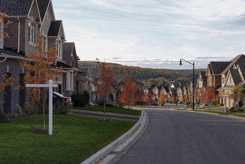 Detached brick and stone houses along a leafy street in fall colours