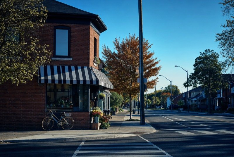 A bicycle parked outside a small shop under a striped awning in a red-brick corner building