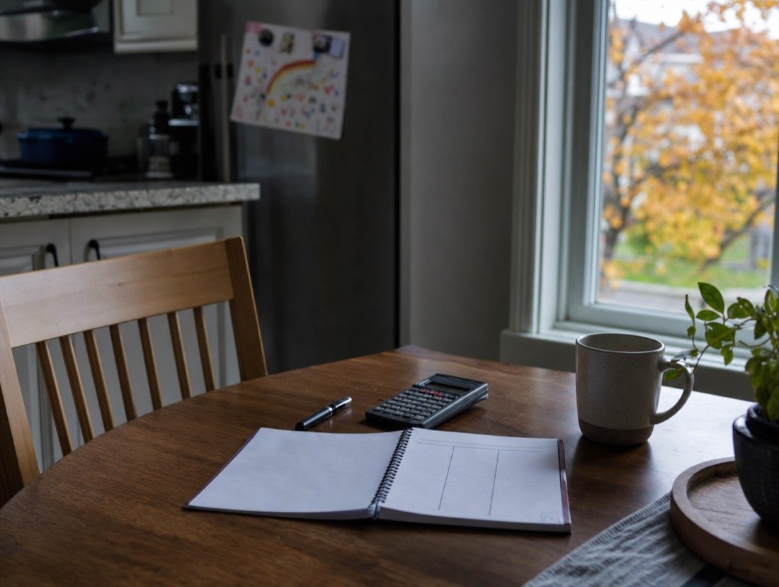 Calculator and open notebook resting on a home table, ready for working out a budget
