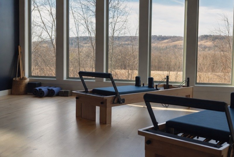Morning light across a pale wood studio floor with rolled mats and training gear